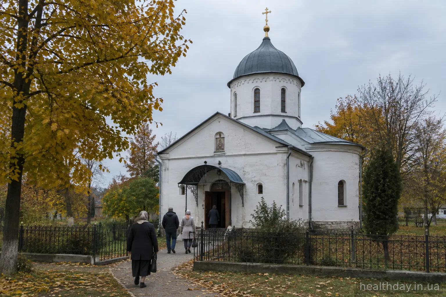 Невелика старовинна українська церква восени, люди йдуть стежкою до входу