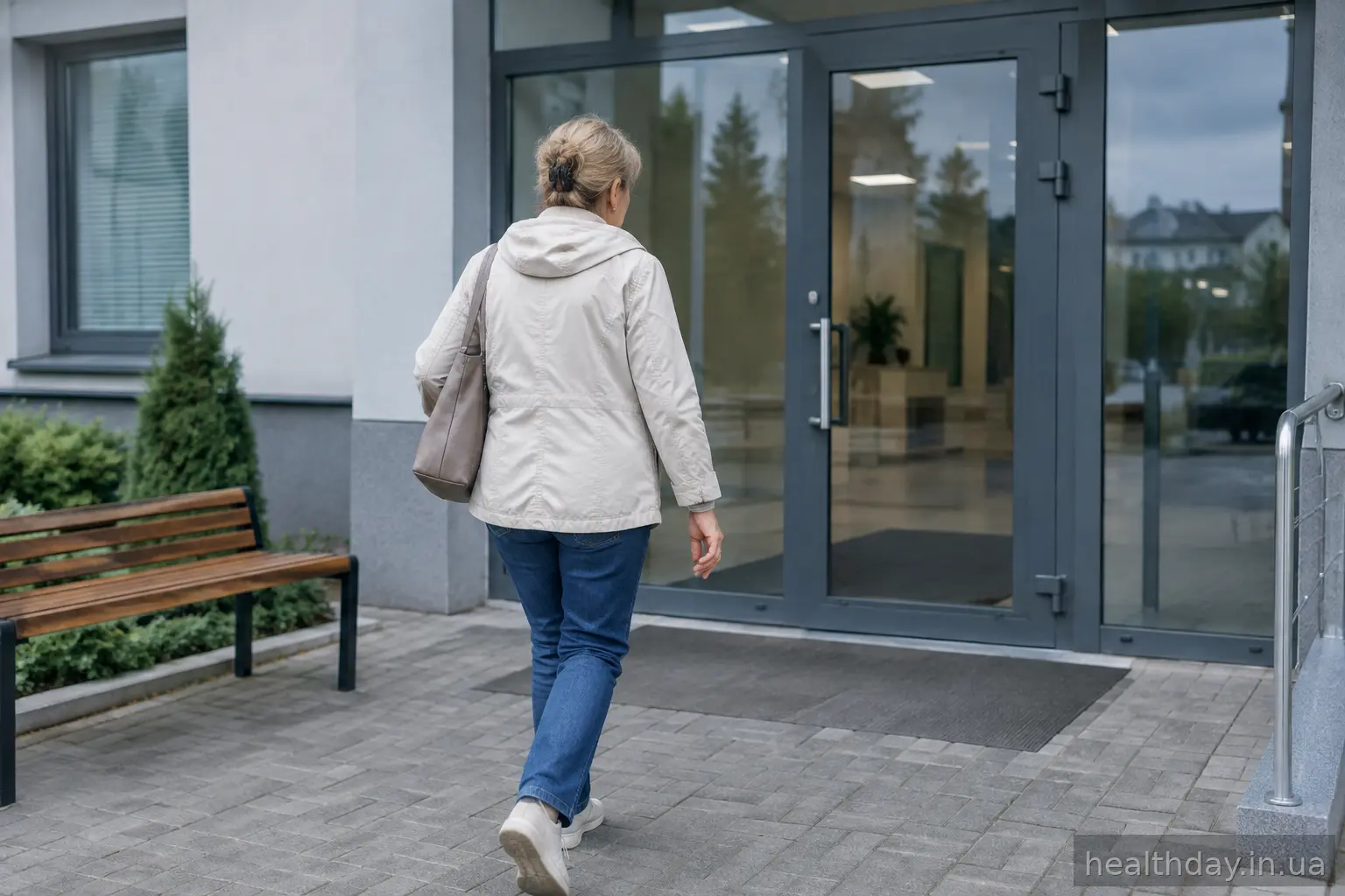 Жінка йде до входу в амбулаторію, тримаючи руку з набряклим пальцем